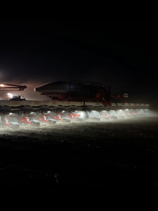 Tractor in a field at night with lights on